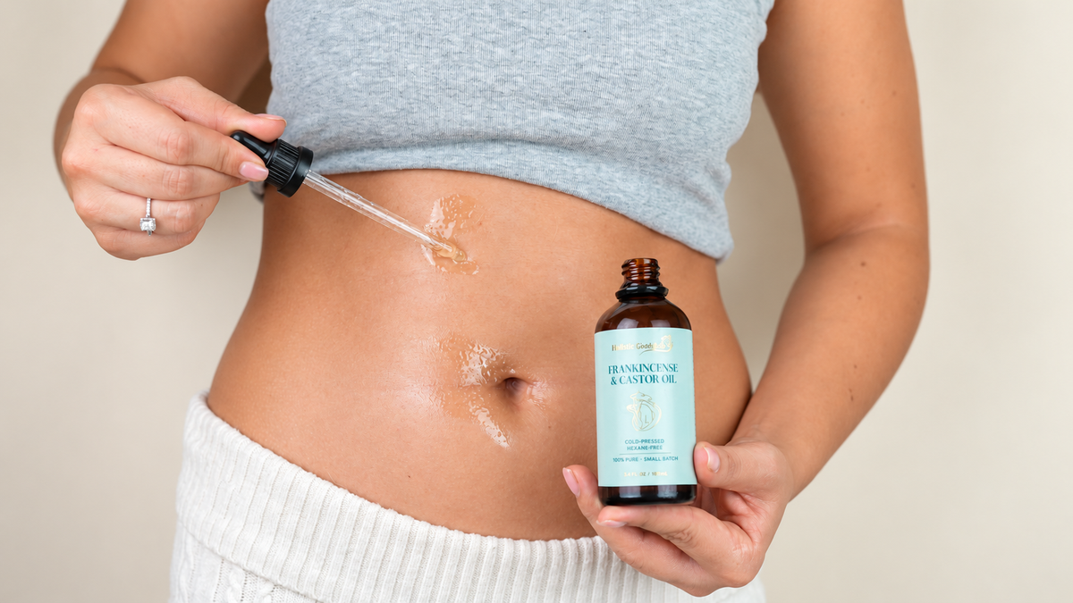 Frankincense and castor oil being applied to the belly with a dropper, bottle held in hand