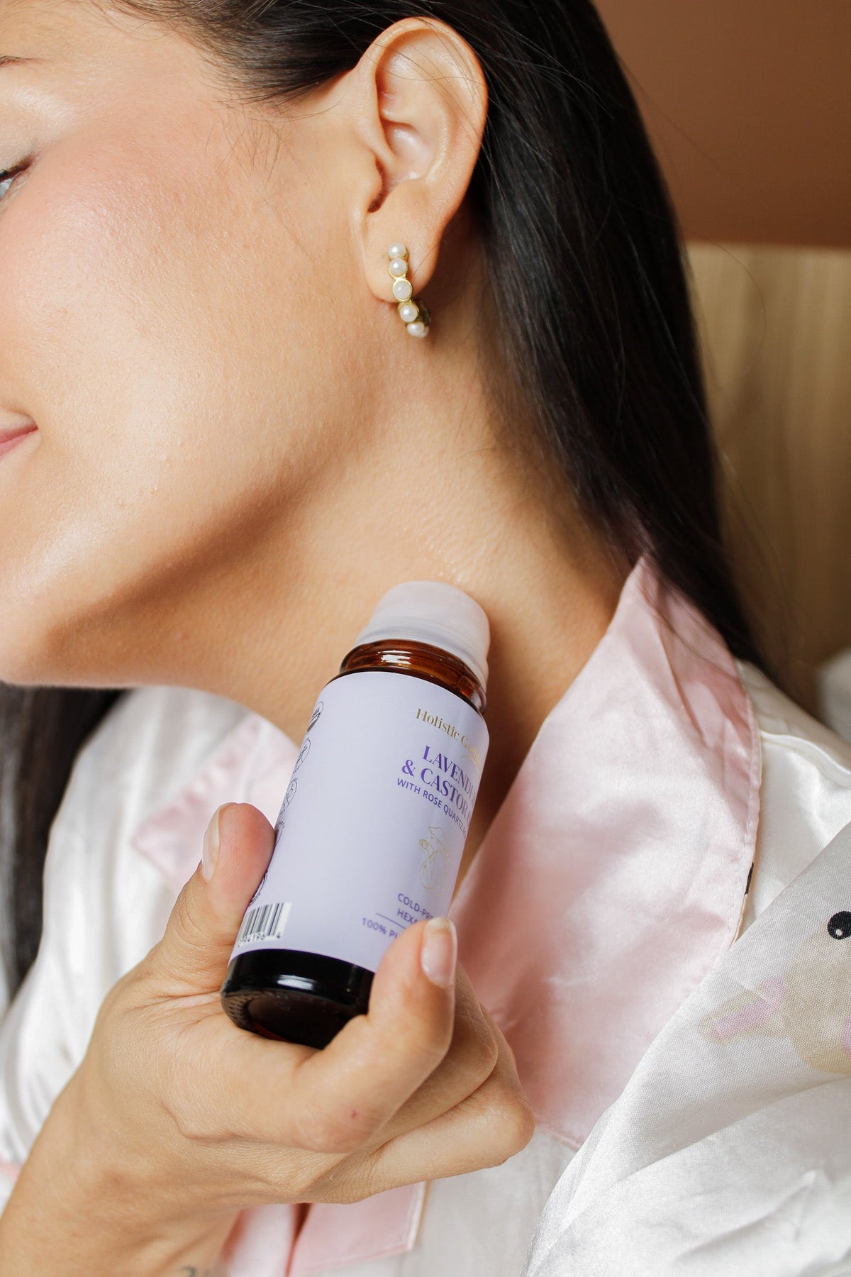 Woman applying Holistic Goddess Lavender & Castor Oil Roll-On to her face