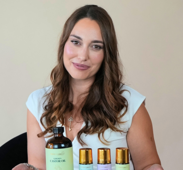 Founder holding a tray with various organic castor oil roll-ons