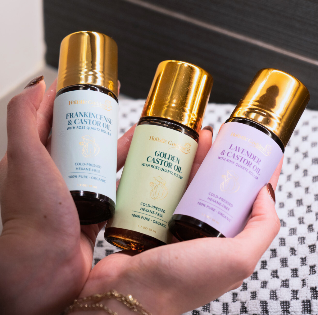 Hands holding the Frankincense, Golden, and Lavender castor oil roll-ons from the Trifecta Kit