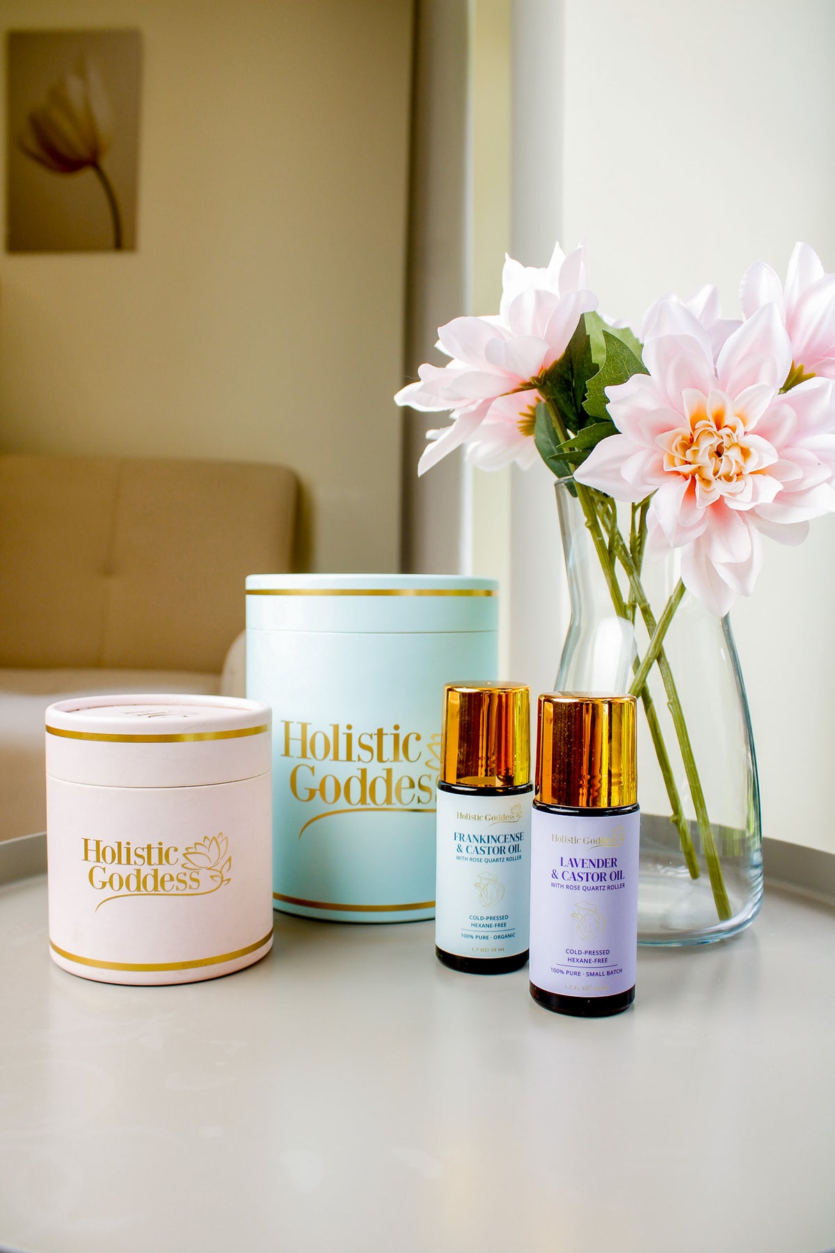 Holistic Goddess Castor Oil Roll-Ons and skincare products styled with flowers