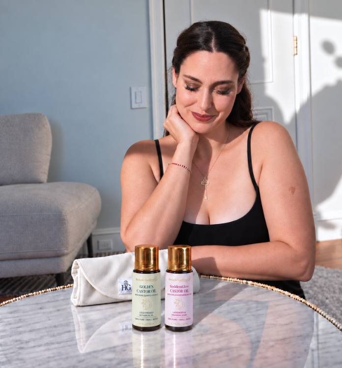 Woman enjoying a self-care ritual with Holistic Goddess Castor Oil products