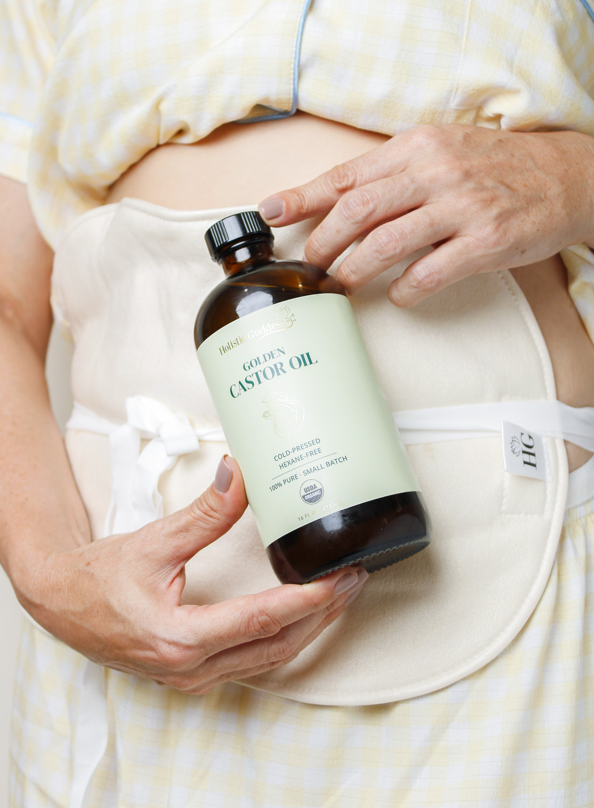 Woman using Holistic Goddess Golden Castor Oil with a castor oil liver pack