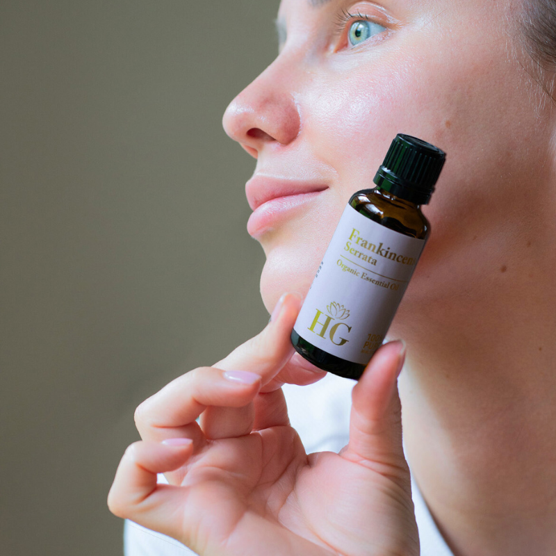 Organic Frankincense Essential Oil by Holistic Goddess – woman holding bottle near face, lifestyle photo