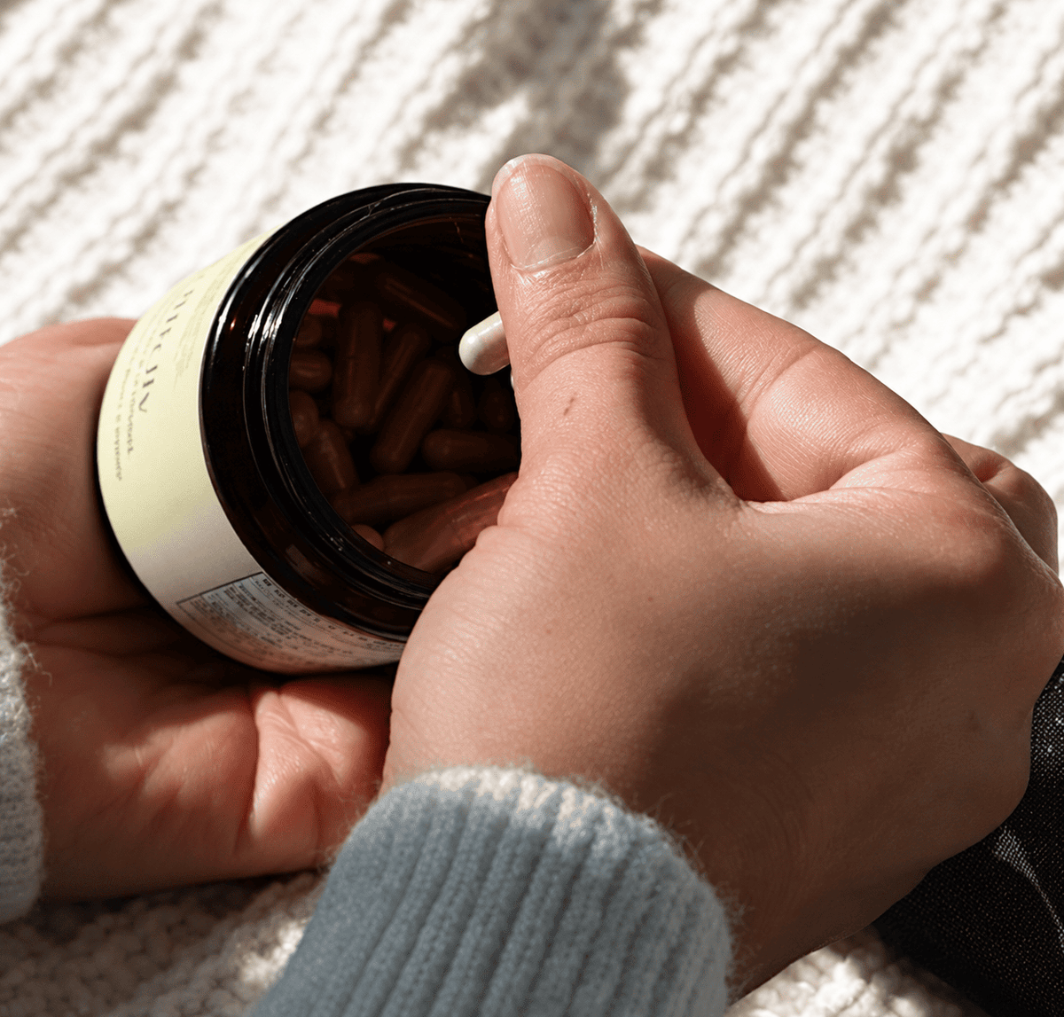WellBelly by Holistic Goddess – hands holding jar on cozy knit blanket, lifestyle photo