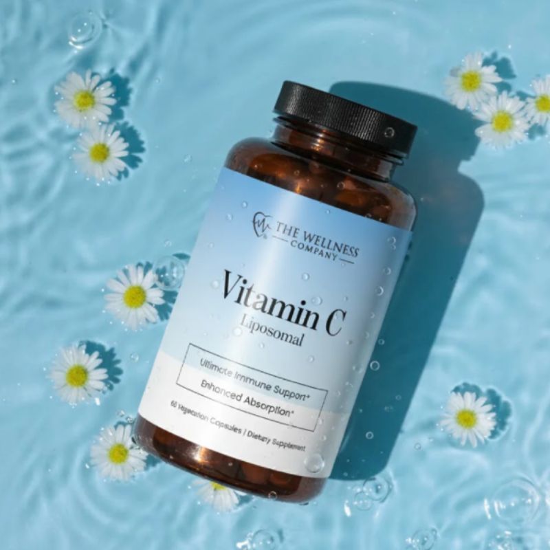 Liposomal Vitamin C – bottle lying on its side in blue water with daisies floating around it, styled lifestyle photo