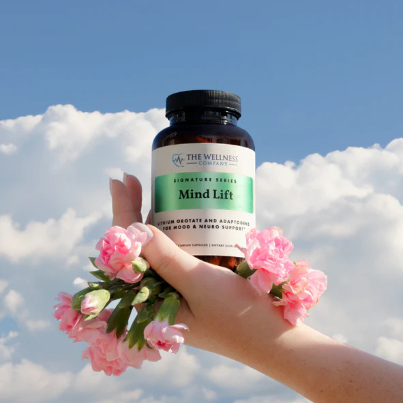 Mind Lift by The Wellness Company – hand holding bottle up against sky with pink flowers, styled lifestyle photo