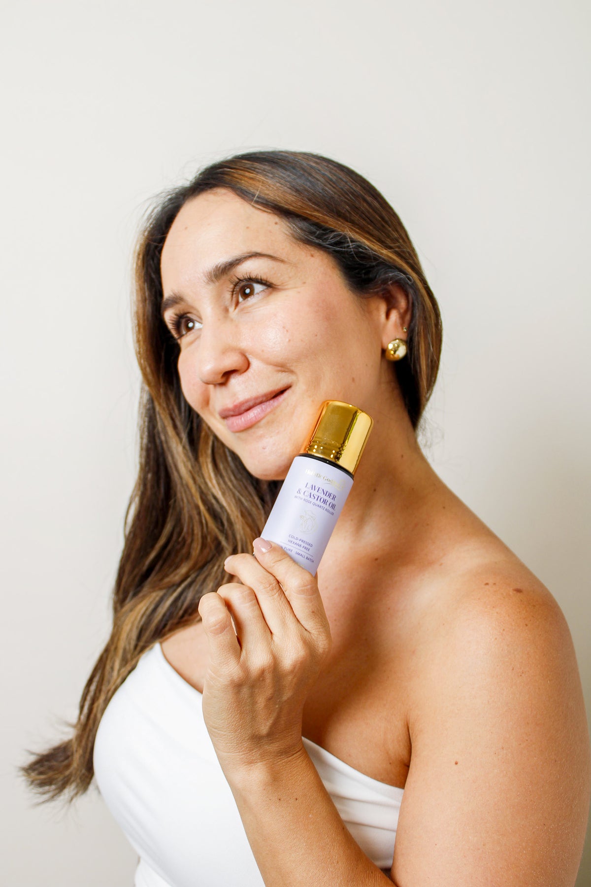 Woman holding Holistic Goddess Lavender & Castor Oil roll-on near her face